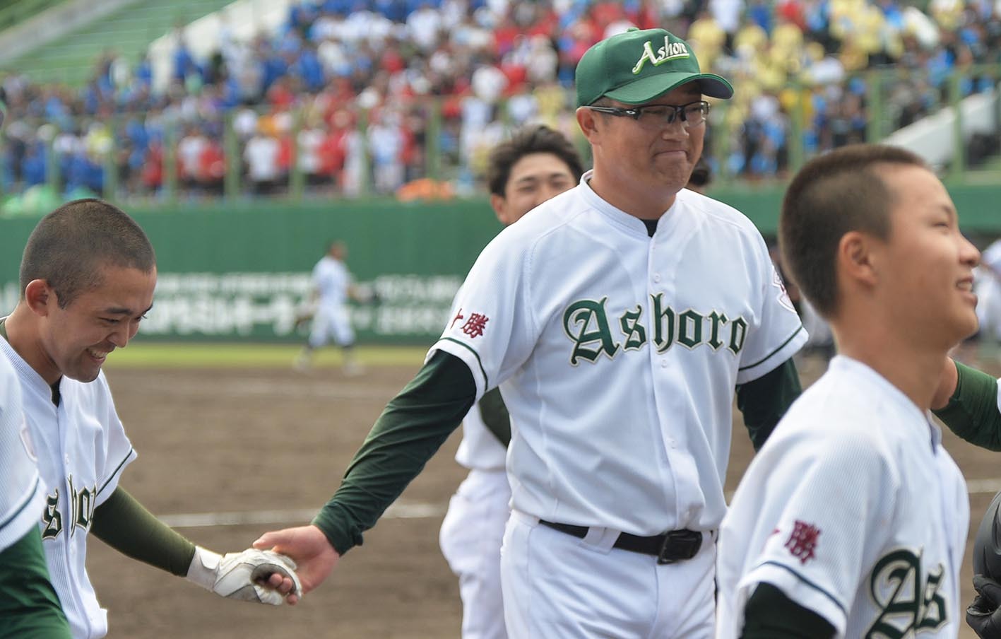 サヨナラ犠飛を放った足寄の佐川（左）とタッチを交わした池田監督