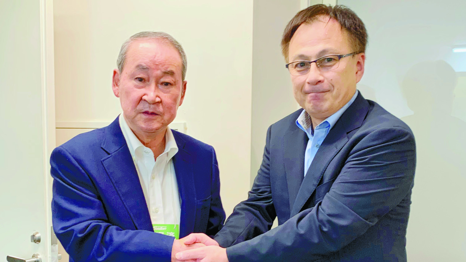 若松元監督（左）と握手を交わす堀松社長（堀松社長提供）