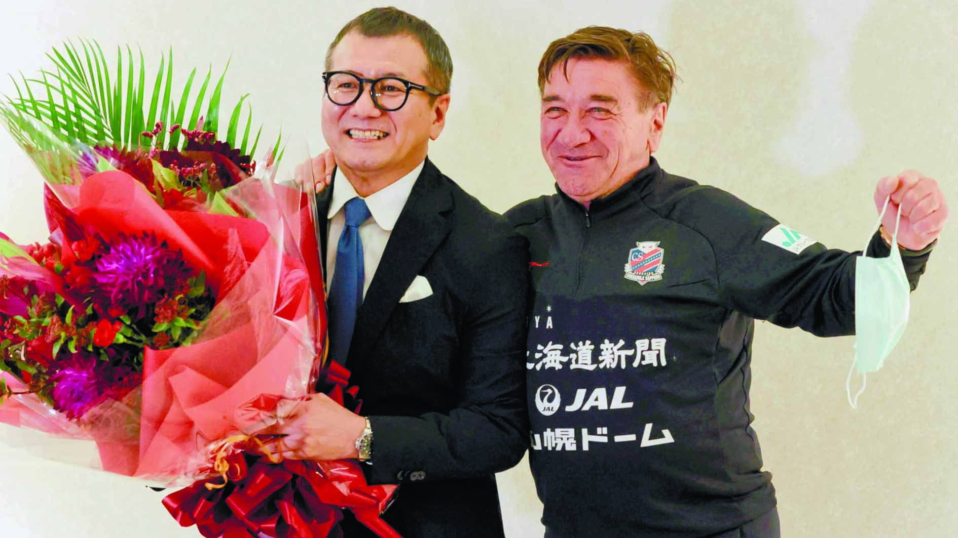 札幌のペトロビッチ監督（右）から花束を贈られ、笑顔を見せる（撮影・舘山国敏）