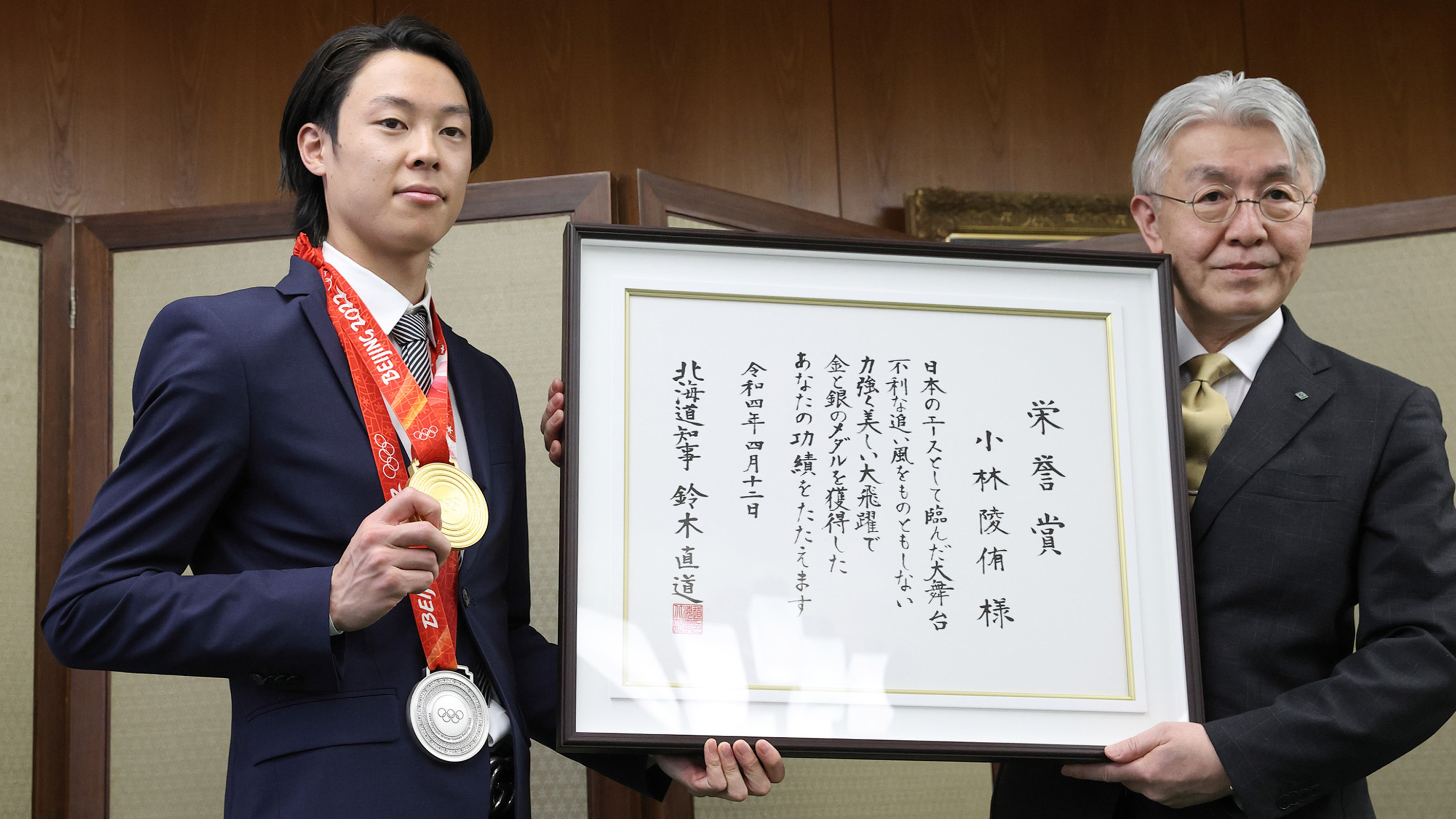 北海道庁で小玉副知事（右）から栄誉賞を受け取り、金メダルをアピールする小林（撮影・中川明紀）