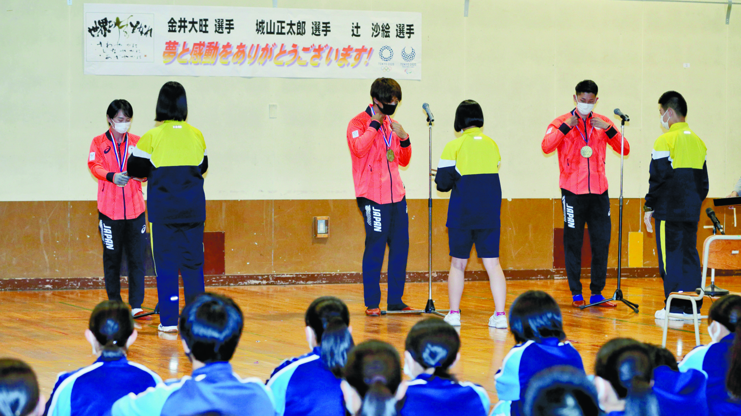 生徒から送られた金メダルをかける（左から）辻、金井、城山の３選手