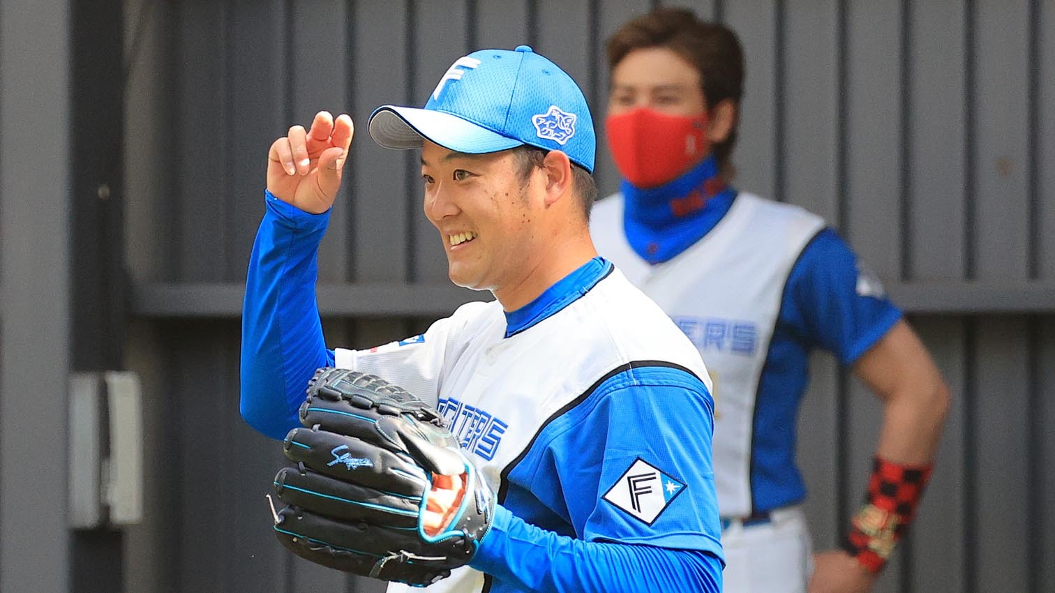 新庄監督(奥)が見守る中、ブルペンで投球する斎藤