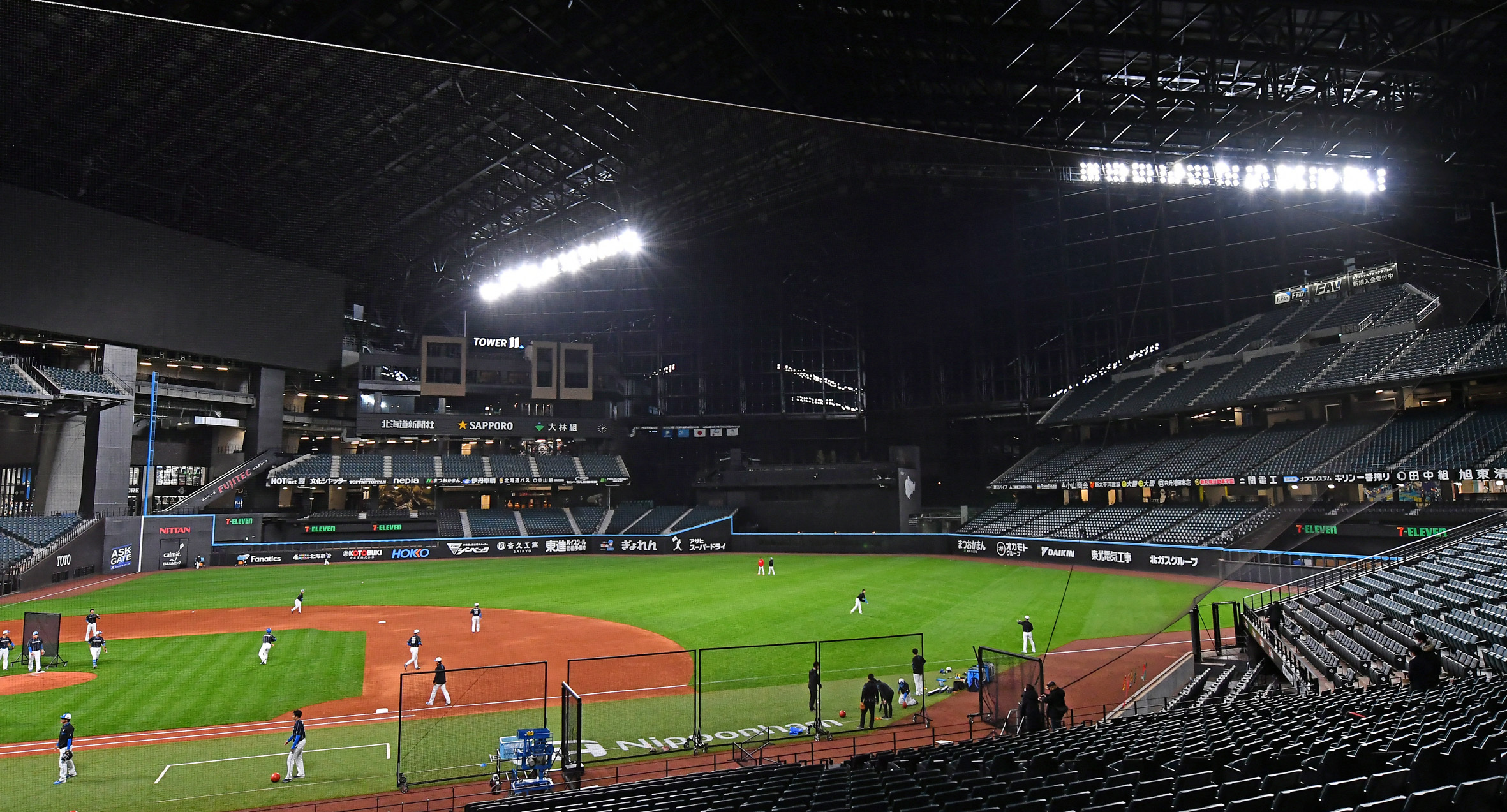 日没後のナイター照明の中、練習する日ハムの選手たち