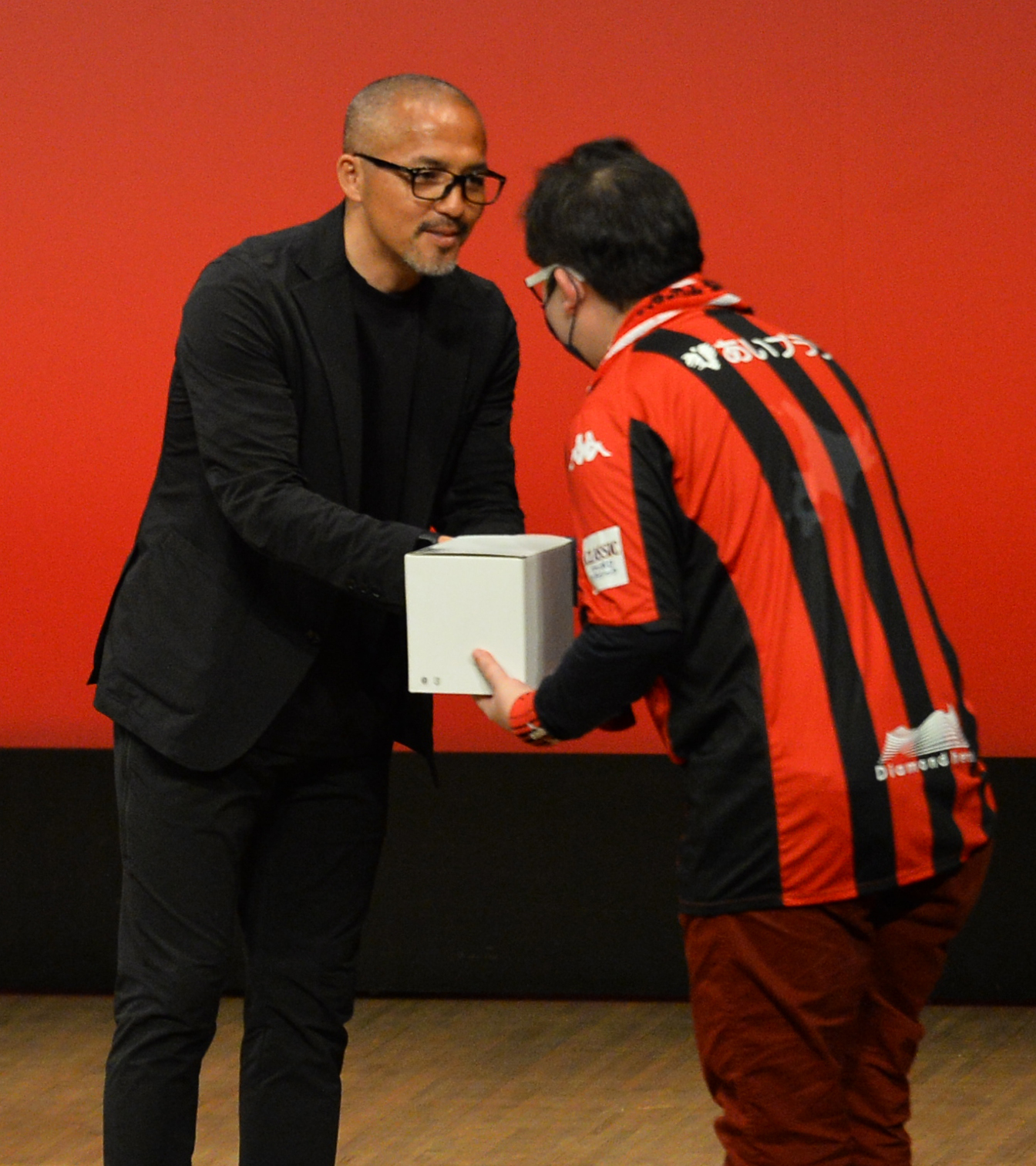 抽選会のプレゼントを渡す小野(左)