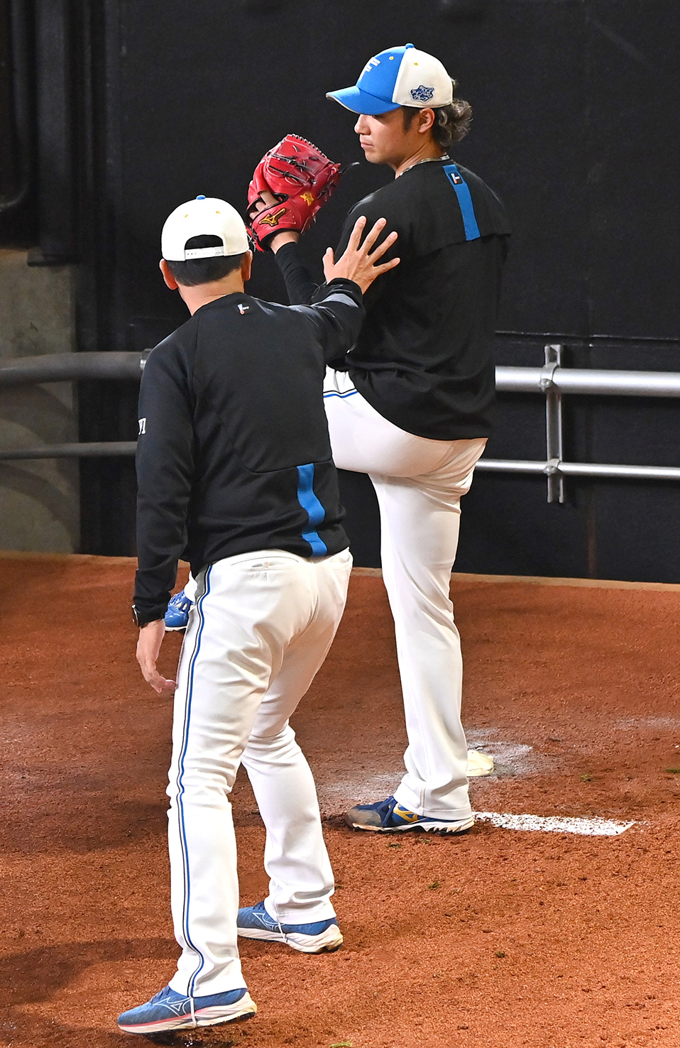 建山コーチ（左）のアドバイスを受けながらブルペンで投球する伊藤
