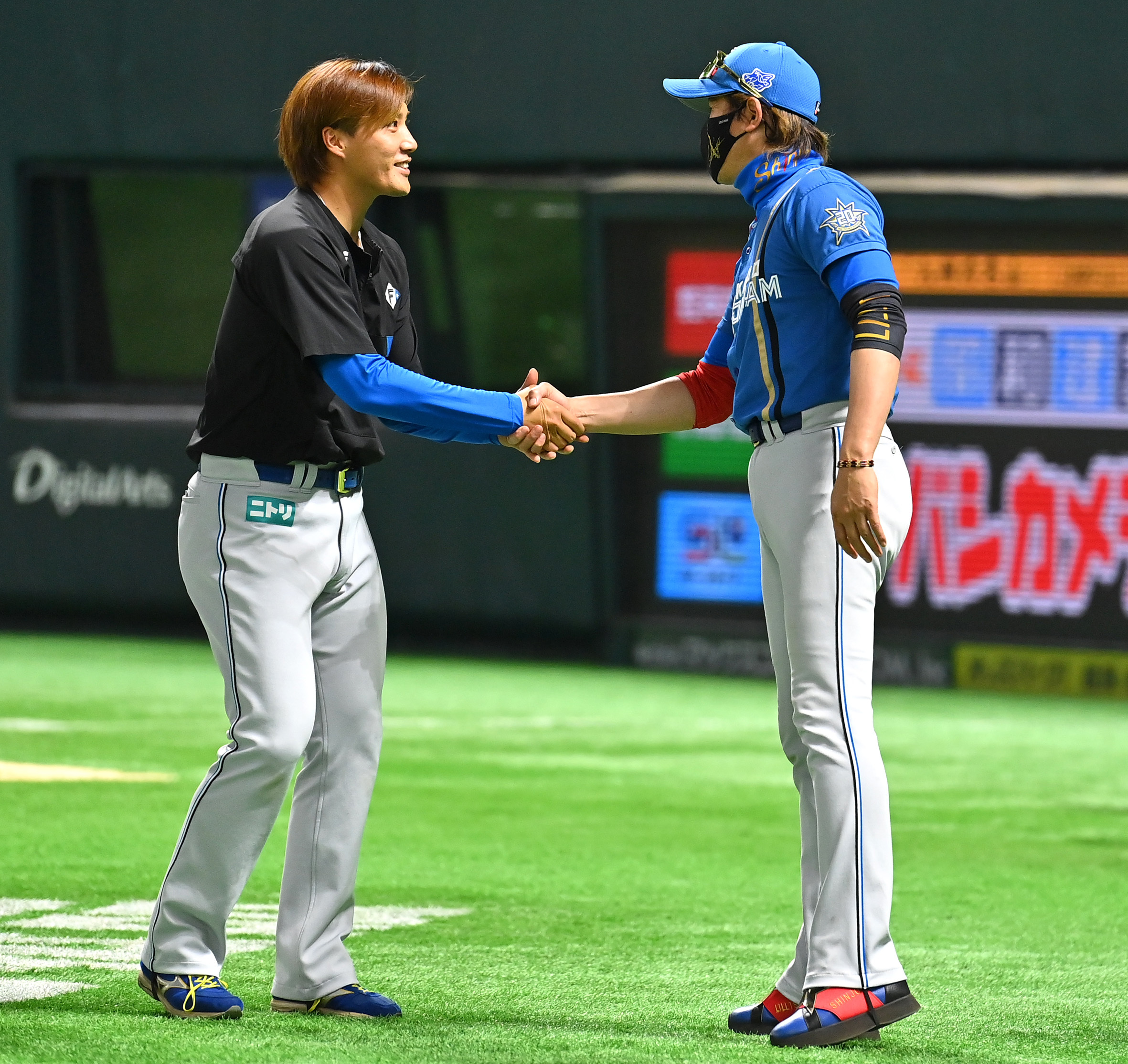 勝利投手の斎藤綱（左）と握手を交わす新庄監督
