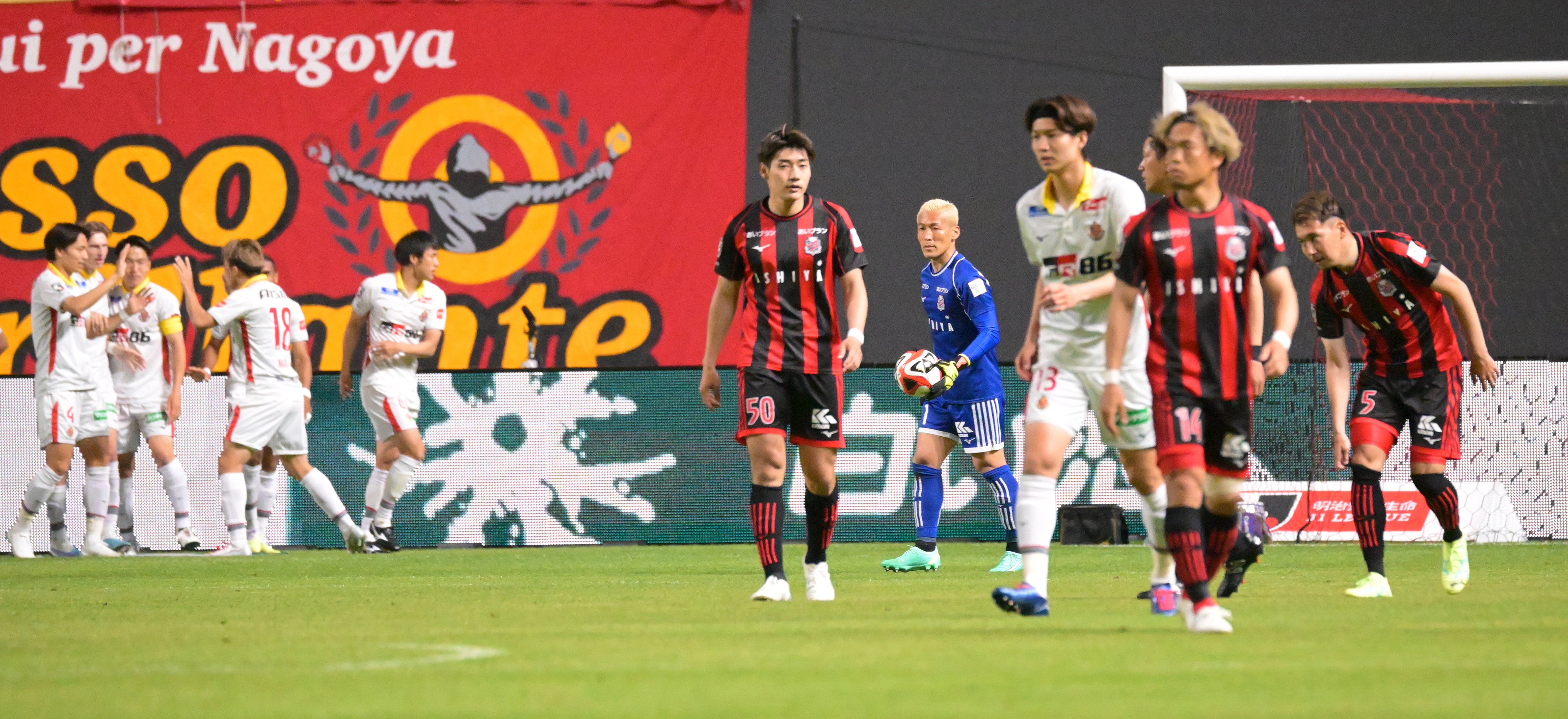 前半開始直後、シュートを決め喜ぶ名古屋のユンカーらと、肩を落とす札幌の選手たち